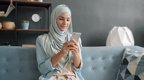 Junge muslimische Frau genießt soziale Medien auf dem Smartphone und bekommt gute Nachrichten beim Lachen in der Moderne