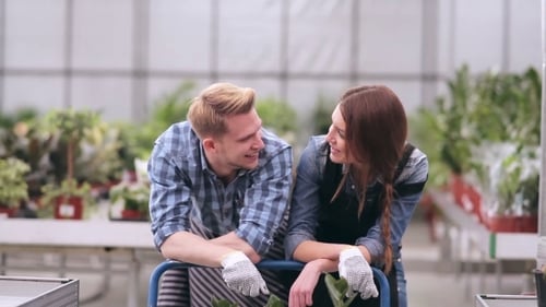 Two Young Adults Smiling in a Greenhouse