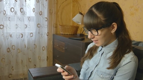 Woman Using Smartphone and Smiling Indoors