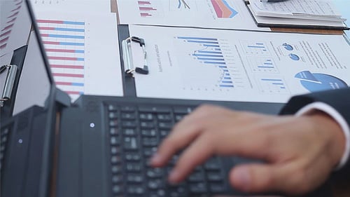 Man typing on laptop with business charts