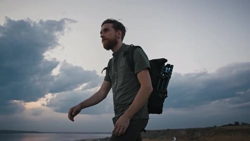 Joven fotógrafo masculino con mochila y trípode en Está caminando por High Hill