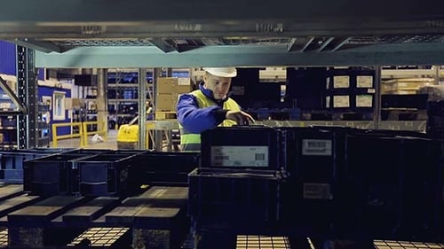 Arbeiter in Uniform geht durch Regale und überprüft Fracht