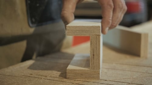 Craftsperson Assembles Plywood with Nail Gun on Workbench