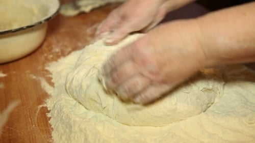 Frau knetet den Teig auf dem Tisch