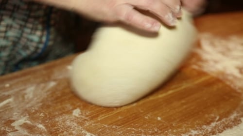Hands Kneading Dough on Wooden Board