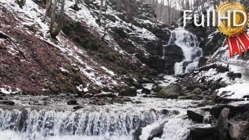 Waterfall Cascades Through Snowy Mountain Forest