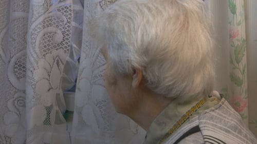 Older Woman Standing By Window At Home