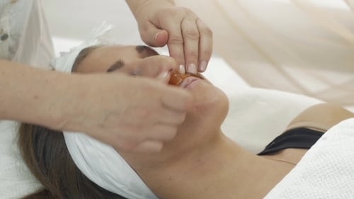 Kosmetikerin legt Shugaring über die Lippen eines Mädchens