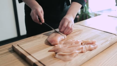 Cozinhe as mãos em fatias finas de frango