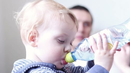 Petit garçon boit de l'eau dans une bouteille