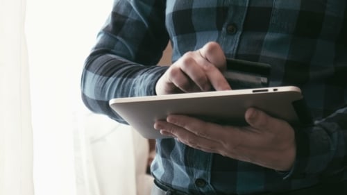 Man Shopping Online Using Tablet and Credit Card