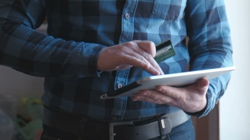 Man Using Tablet and Credit Card Indoors