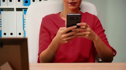 Woman Smiling While Using Phone in Office Setting