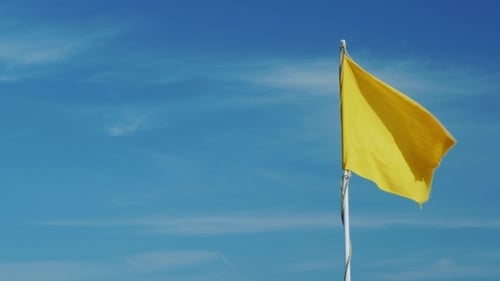 Yellow Warning Flag Waving in Wind