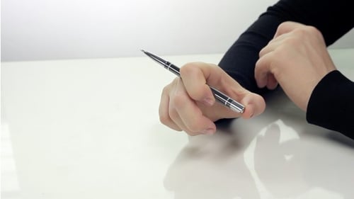 Hand Fidgeting with Pen on White Table
