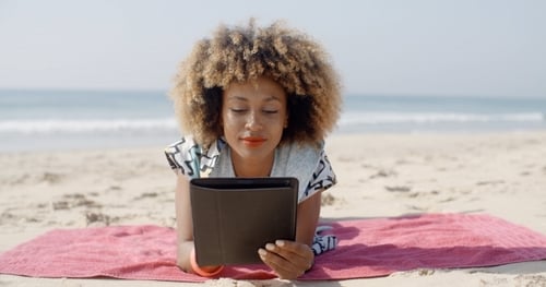Woman Uses A Tablet On The Beach