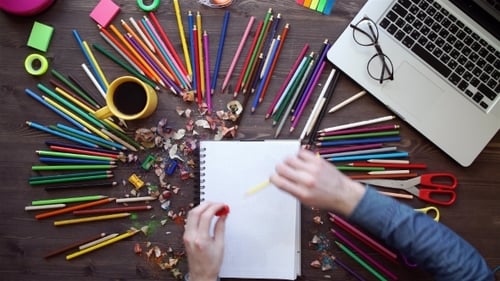 Sharpening Pencil in Creative Workspace with Colorful Supplies