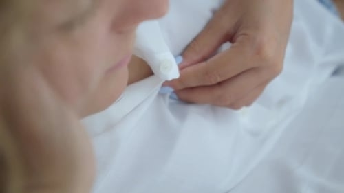 Woman Buttoning White Shirt in Morning Light