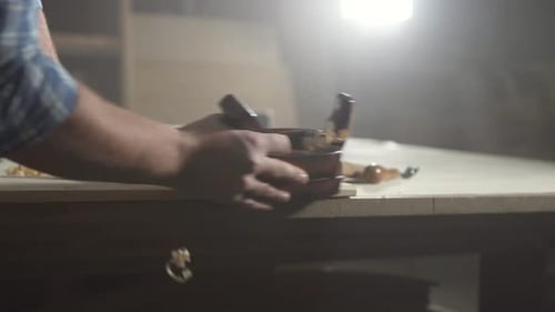 Hands of a Carpenter in a Workshop with a Plane Flies Shavings