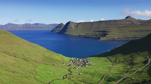 Drohne fliegt über grasbedeckte Klippe und blaues Meer