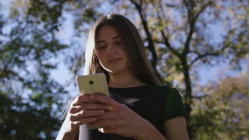 An Attractive Young Lady Using a Phone in Town. Medium Shot
