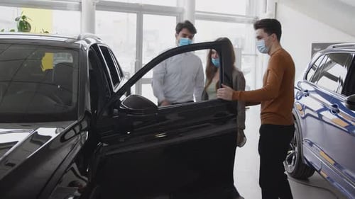 Salesman Opens Car Door For Customer in Showroom