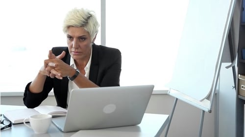 Woman Thinking Seriously at Desk in Bright Office