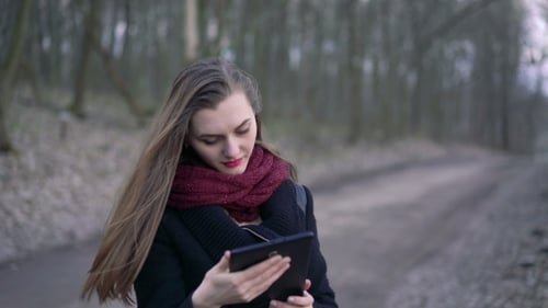 Young Woman Using Tablet in Forest Path
