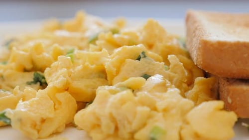 Tasty omelete with green fresh scallion and toasted bread on ceramic plate slow panning 4K 2160p UHD