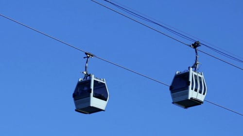 Cable Car Gondolas Move Across Clear Blue Sky