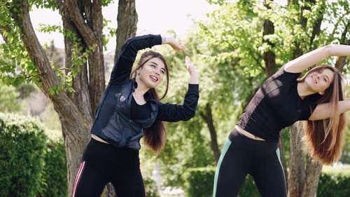 Women Exercising and Stretching in Urban Park