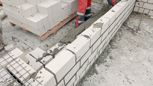 Construction Worker Laying White Bricks to Build Wall