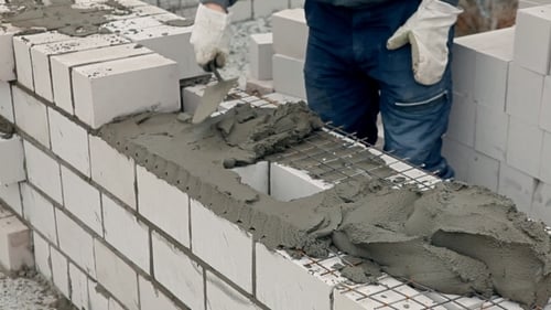 Tradesman Laying White Brick Wall at Construction Site
