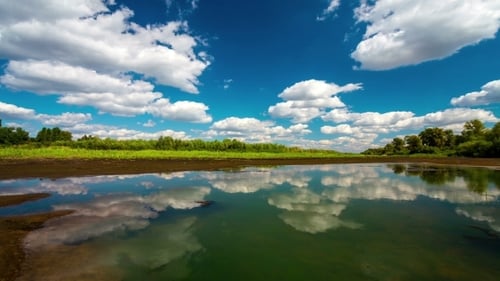 Mit fließenden Wolken mit Spiegelung im Wasser und tiefblauem Himmel