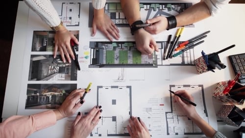 Vier Architekten diskutieren gemeinsam am Schreibtisch über den Plan Timalaps