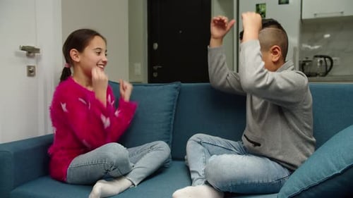 Girl and Boy Play Hand Game on Couch