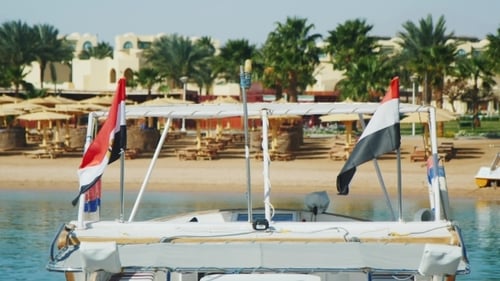 Picturesque Tropical Beach Scene with Egyptian Flags on Boat