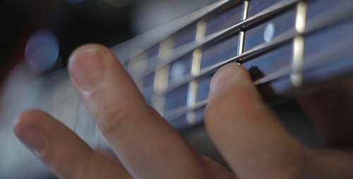 Hand Playing Four String Bass Guitar Close Up