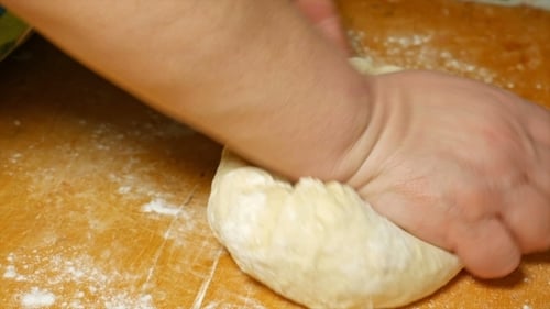 Hands Kneading Dough on Cutting Board
