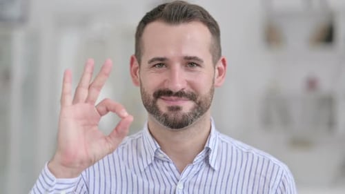 Man Gives Okay Sign Smiling Indoors Close-up