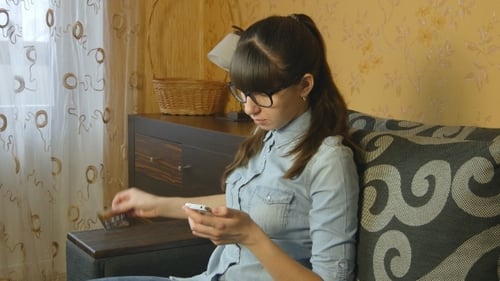 Woman Using Phone with Credit Card Indoors