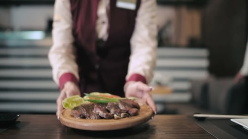 Waiter Serves Customers In Restaurant.