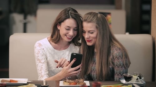Two Women Friends Looking at Smartphone in Restaurant