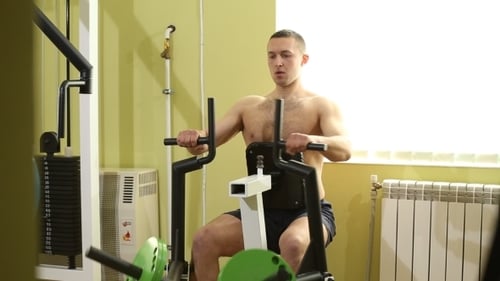 Man Using Rowing Machine for Exercise in Gym