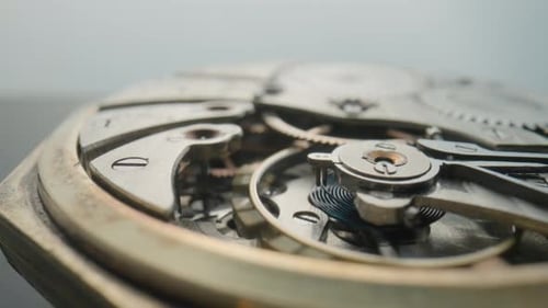 Macro Shot of the Internal Parts of Antique Pocket Watch on a Light Gray Studio Background