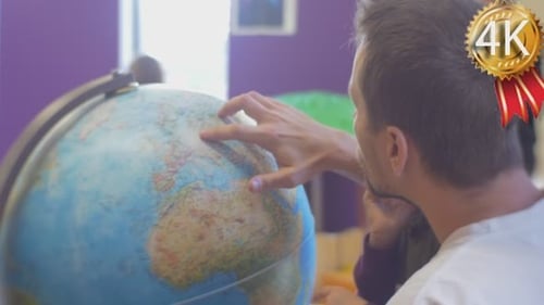 Child and Adult Exploring Globe in School