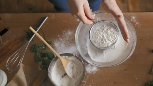 Hands Sifting Flour in Bright Kitchen
