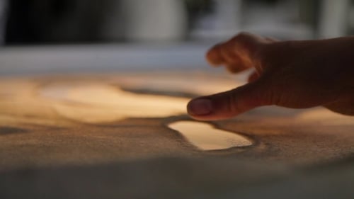 Mädchen zeichnet Gemälde mit Sand auf dem Glas