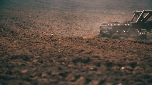 Traktor pflügt Feld bei Sonnenuntergang