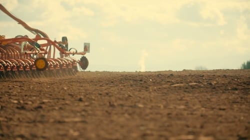Traktor pflügt Feld bei Sonnenuntergang